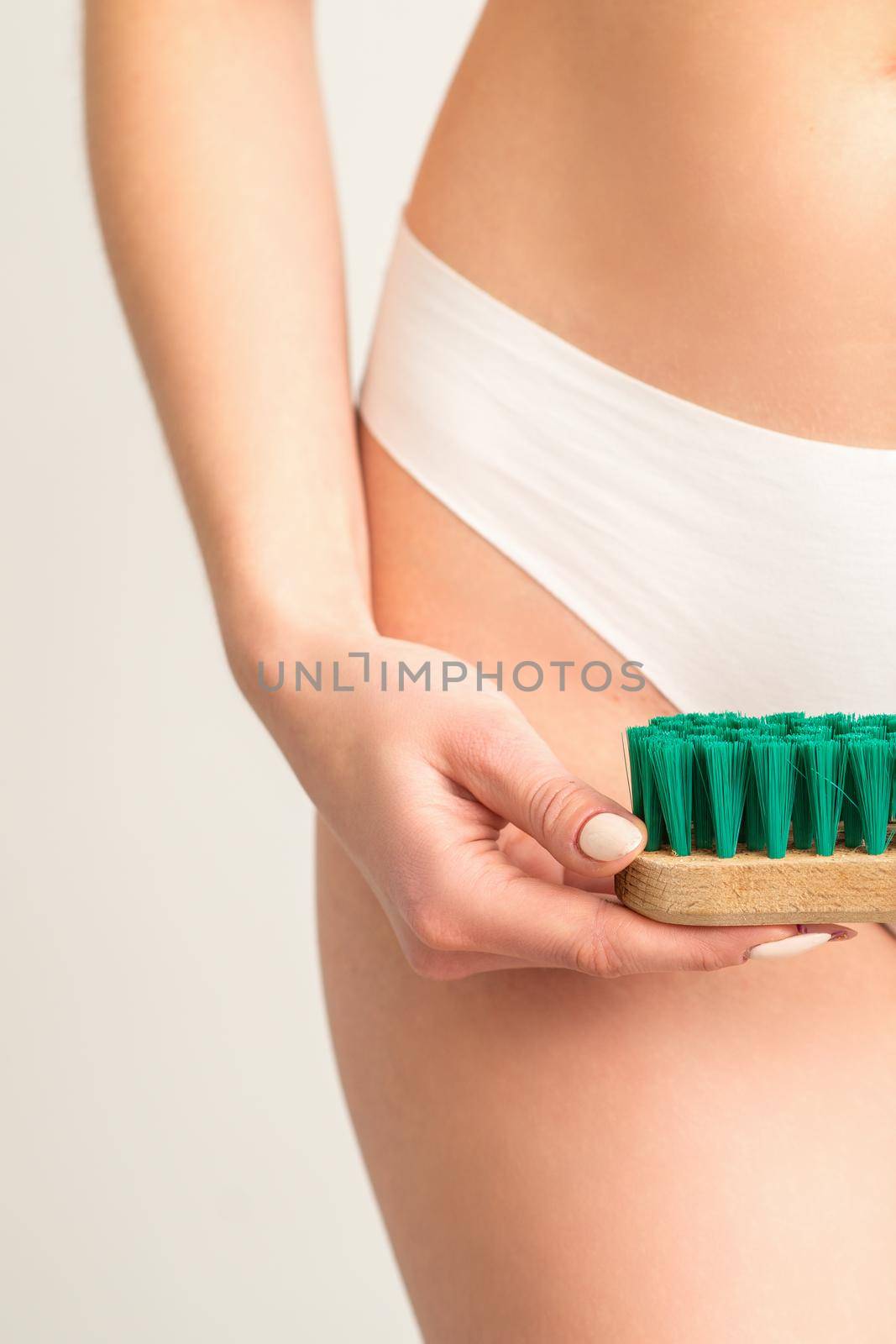 A woman in white panties holds a clothes brush on a white background. Depilation on the bikini zone. by okskukuruza