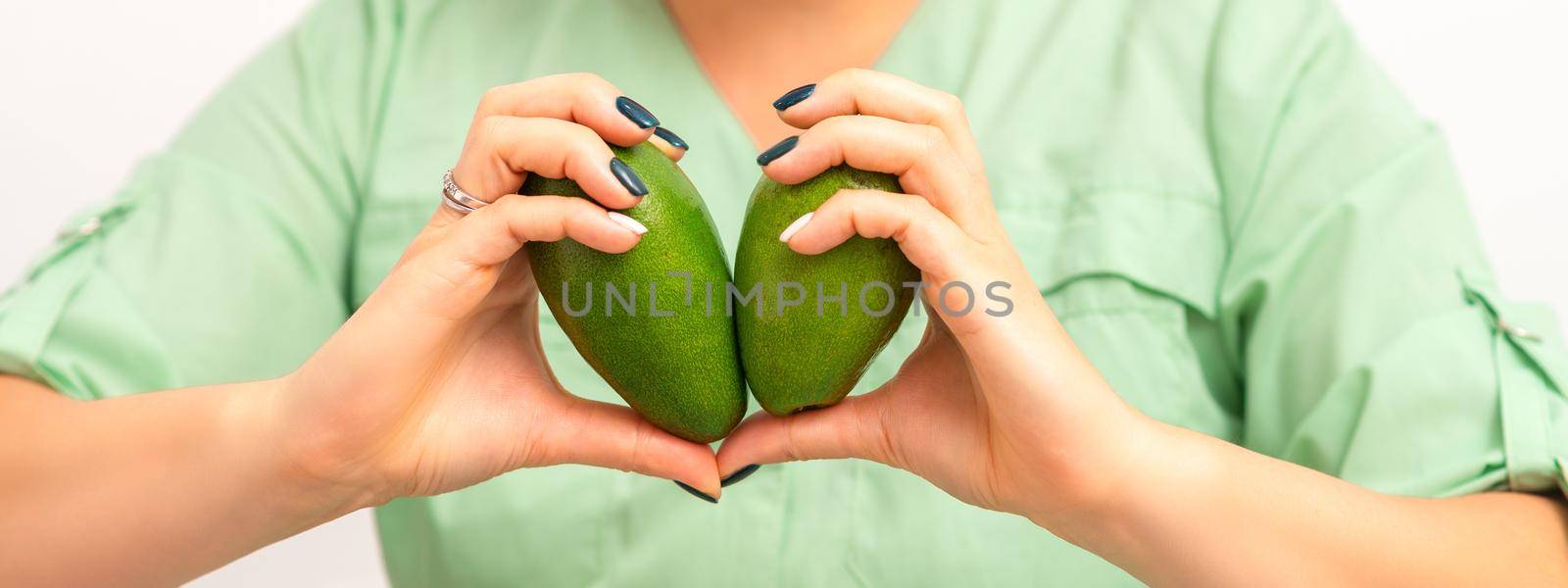 Female nutritionist doctor holding organic avocado fruit. Healthy lifestyle concept. by okskukuruza