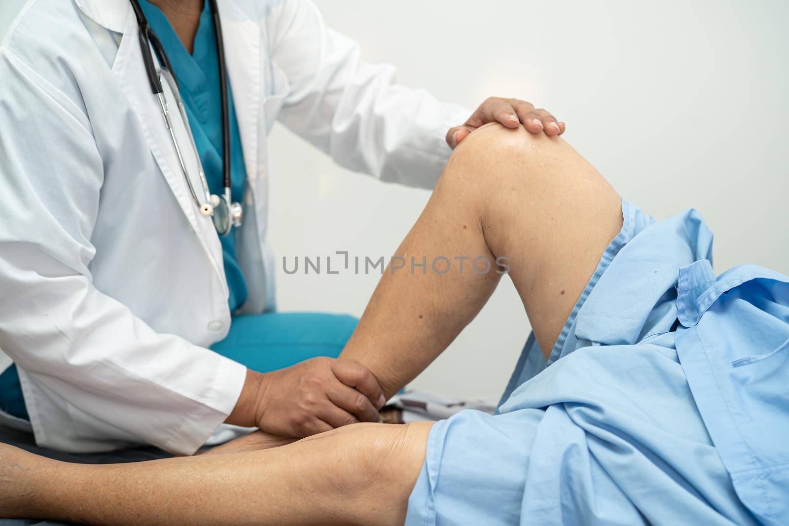 Asian doctor physiotherapist examining, massaging and treatment knee and leg of senior patient in orthopedist medical clinic nurse hospital. by pamai
