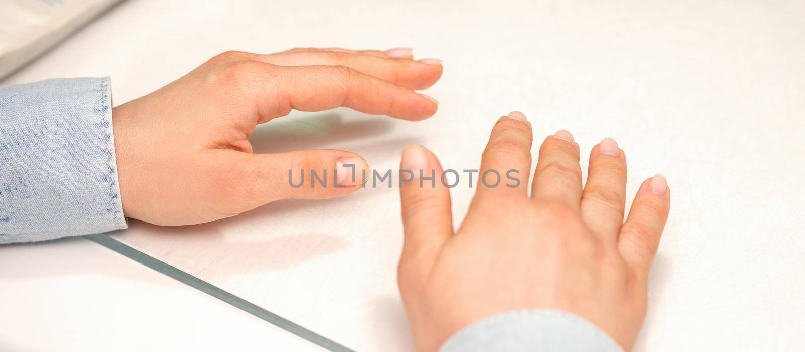 Hands of a young woman with well-groomed nails on the manicure table