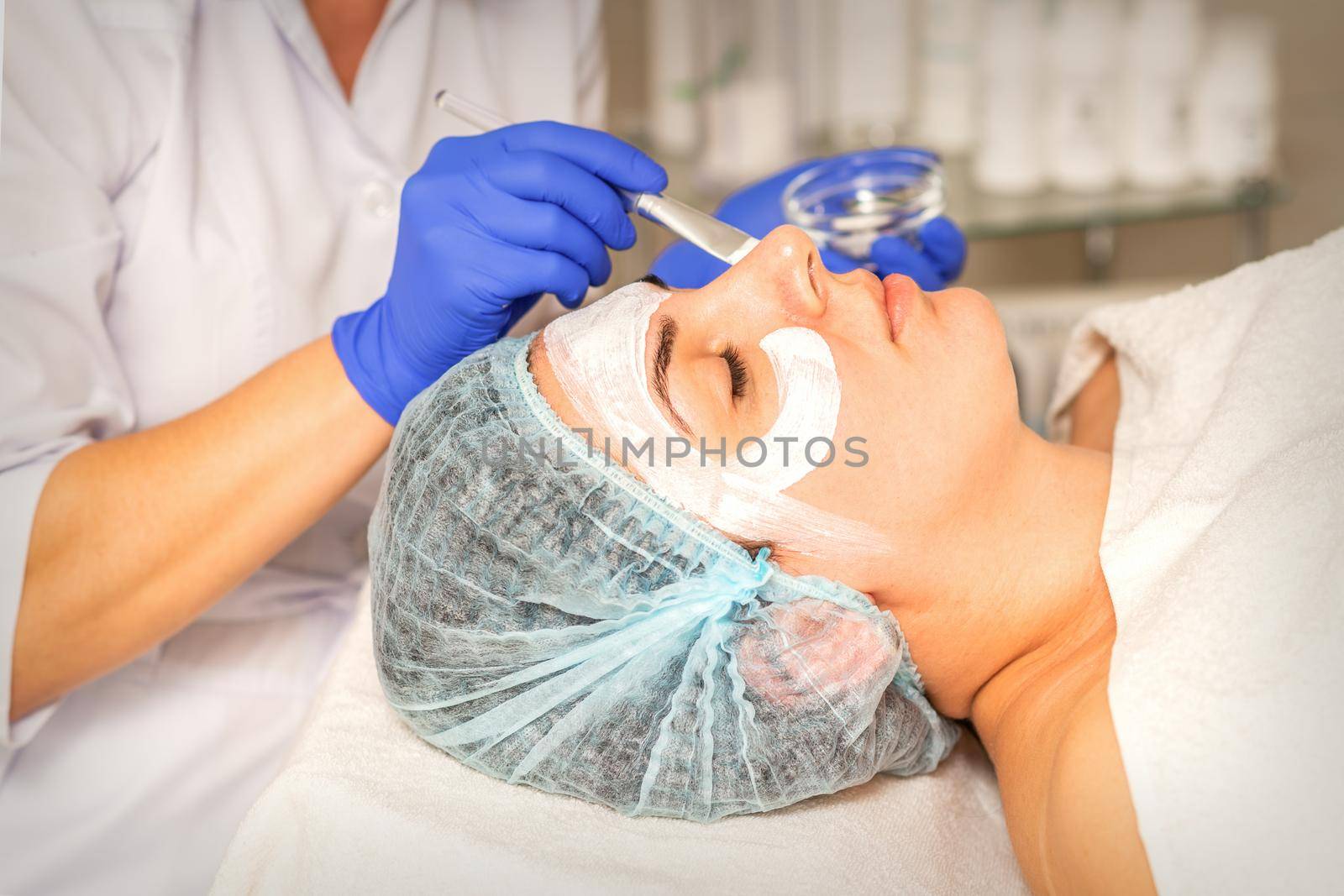 Face peeling at the beautician. Facial treatment. The beautician applies a cleansing face mask to the female patient