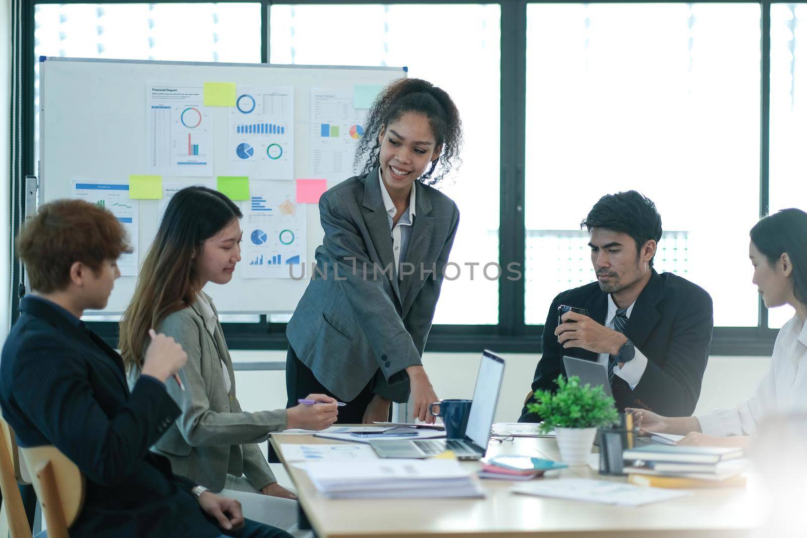 Asian business woman leader in a meeting with her multi-ethnic colleagues at the office presenting sales data or forecast for a project.