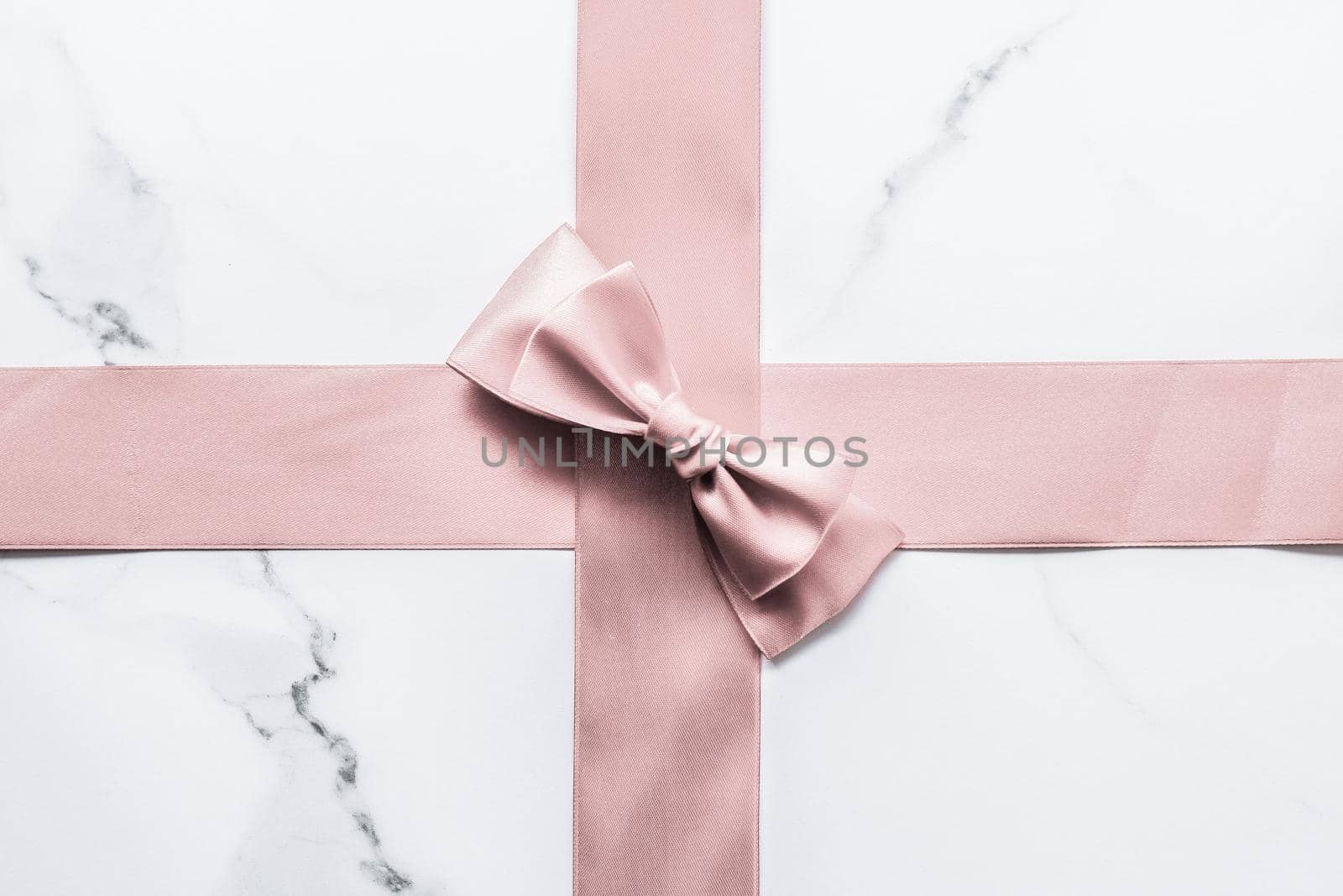 Birthday, wedding and girly branding concept - Beige silk ribbon and bow on marble background, glamour present mockup and fashion gift decoration for luxury beauty brand holiday flatlay design