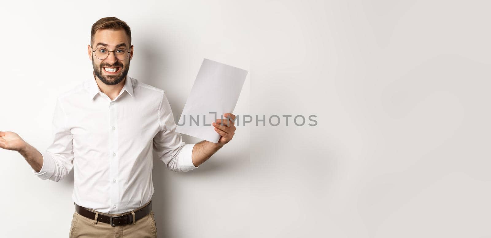 Awkward manager showing document and shrugging, looking guilty of mistake, standing over white background.