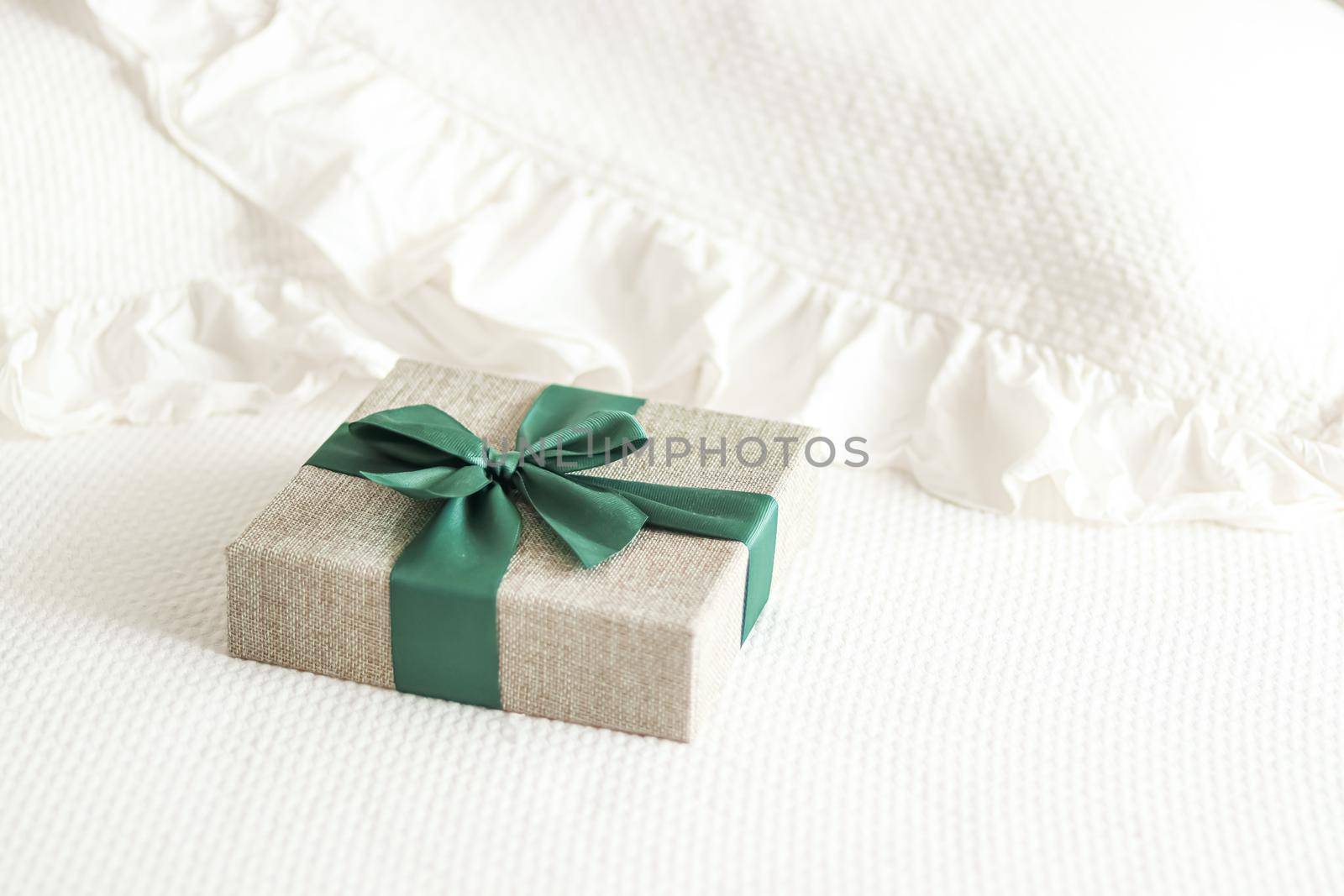 Holiday present and luxury online shopping delivery, wrapped linen gift box with green ribbon on bed in bedroom, chic countryside style, close-up