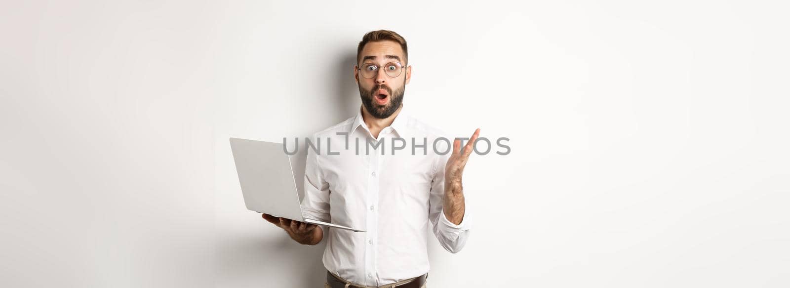 Business. Man holding laptop and looking amazed, surprised with website, standing over white background. Copy space