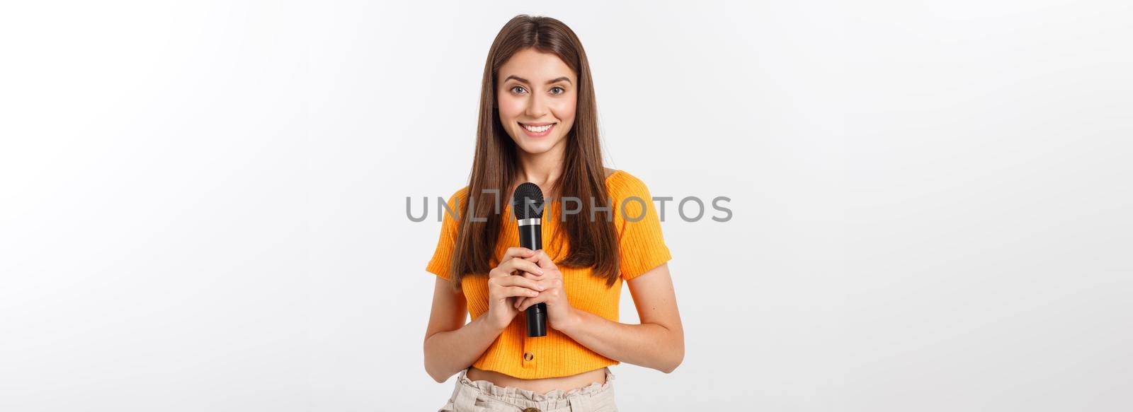 Young pretty woman happy and motivated, singing a song with a microphone, presenting an event or having a party, enjoy the moment.