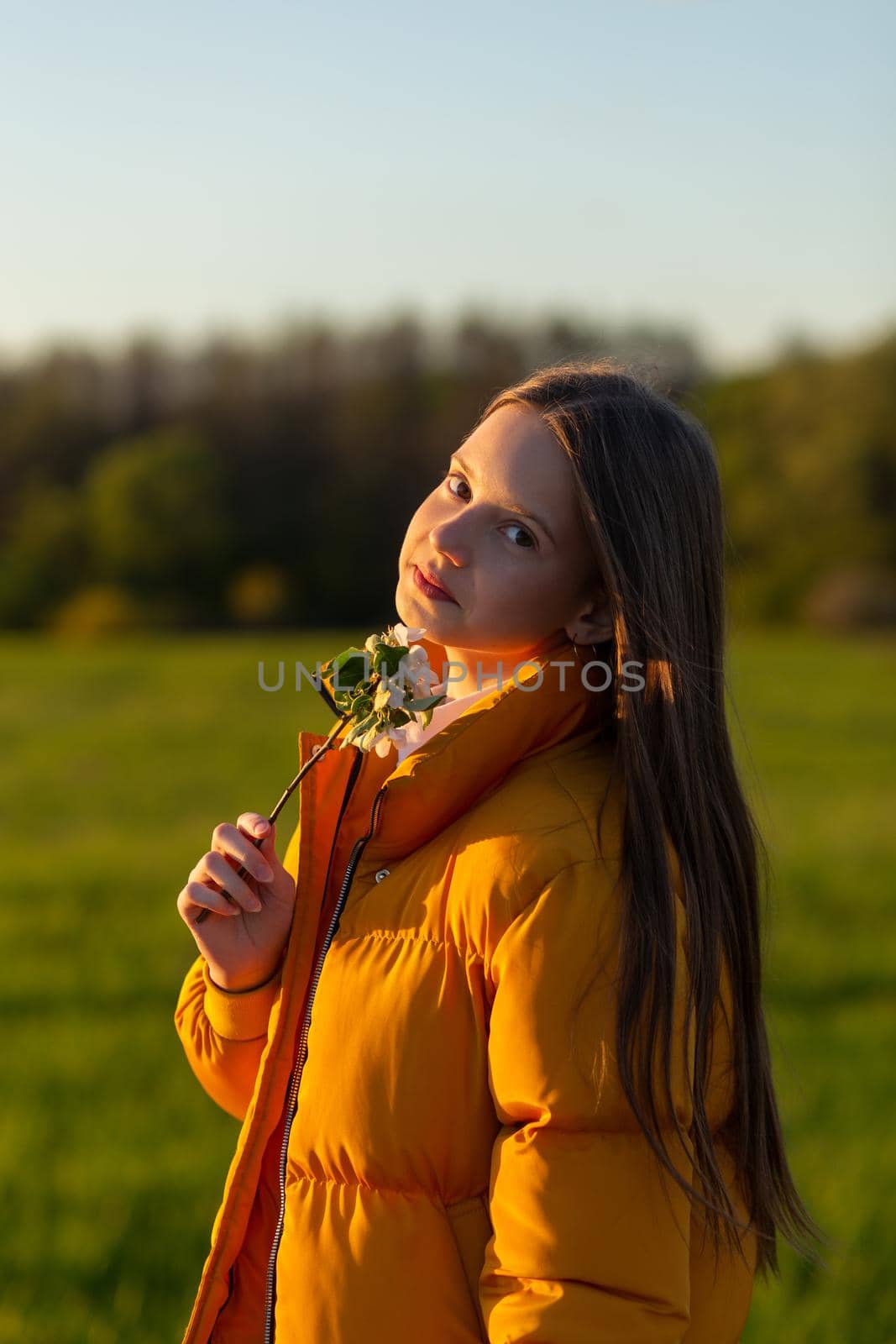 Portrait of a beautiful casual weared teenage girl outdoors in spring. A girl poses with blooming cherry brunch.