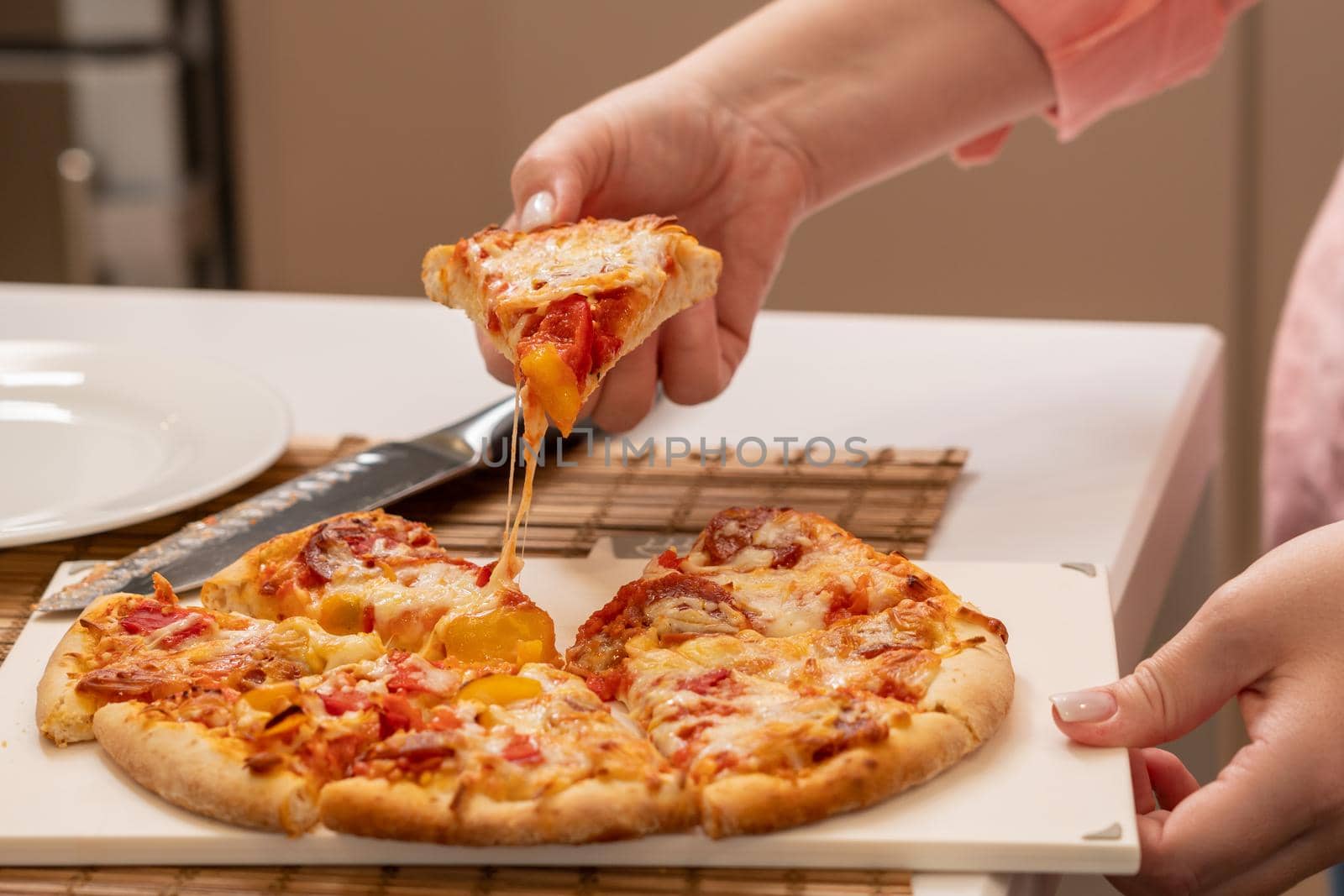 Raised slice of pizza before eating it and stretching strands of cheese.