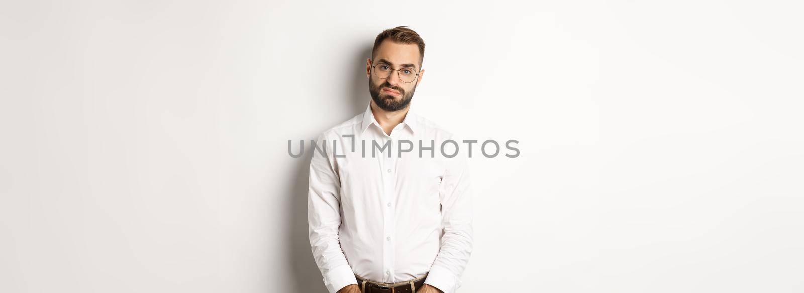 Sad and gloomy office manage frowning, standing tired against white background.
