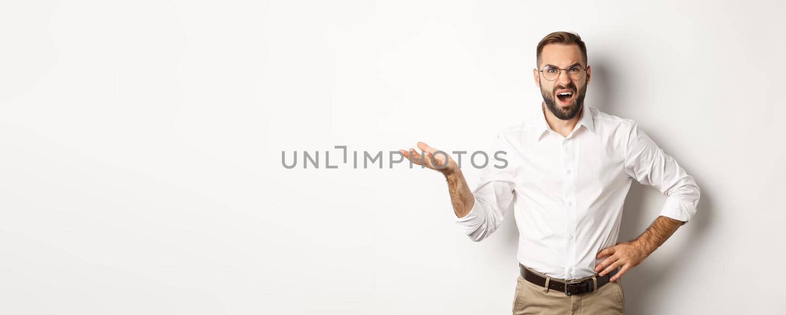 Frustrated office worker complaining, gesturing and looking disappointed, standing over white background.