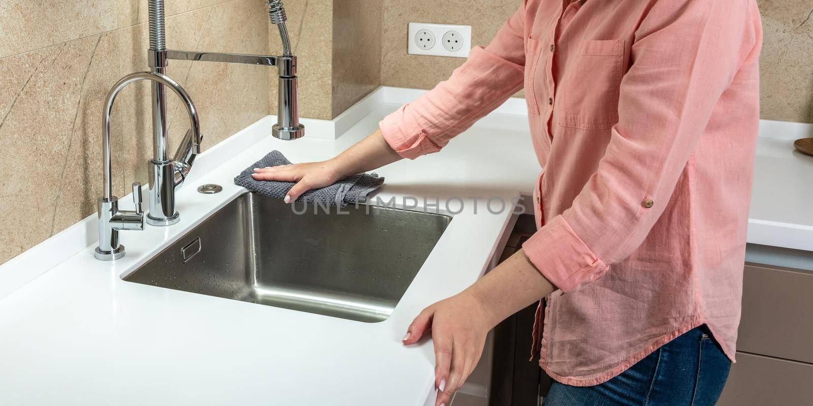 Woman housewife wipes the countertop in the kitchen with a rag.