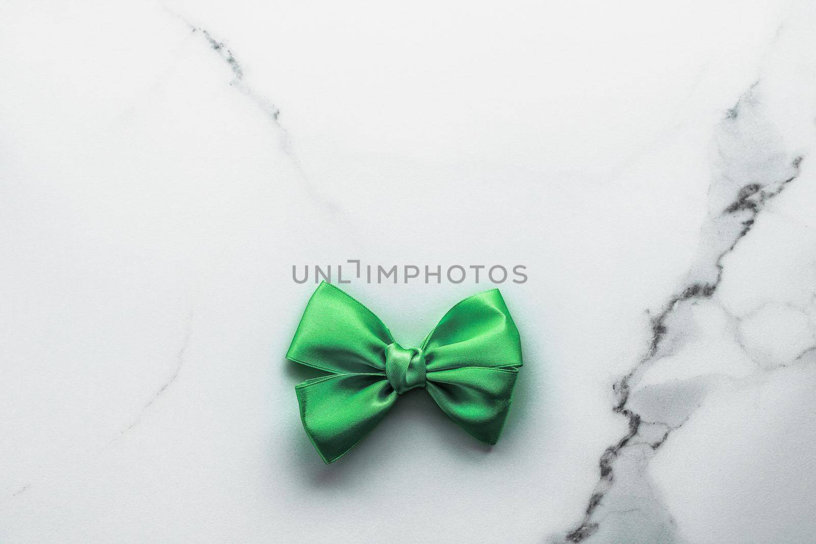 Green silk ribbon and bow on marble background, St Patricks day present or Christmas glamour gift decor for luxury digital brand, holiday flatlay design by Anneleven