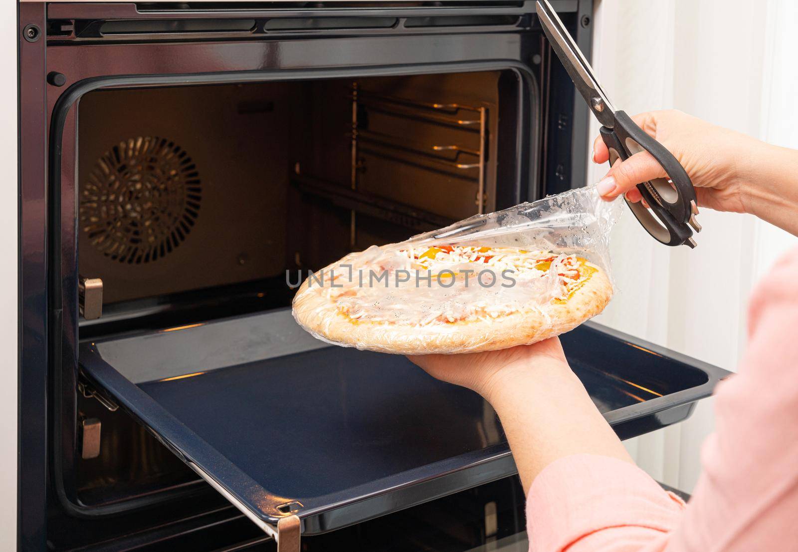 Removing the packaging from the pizza before placing it in the oven.