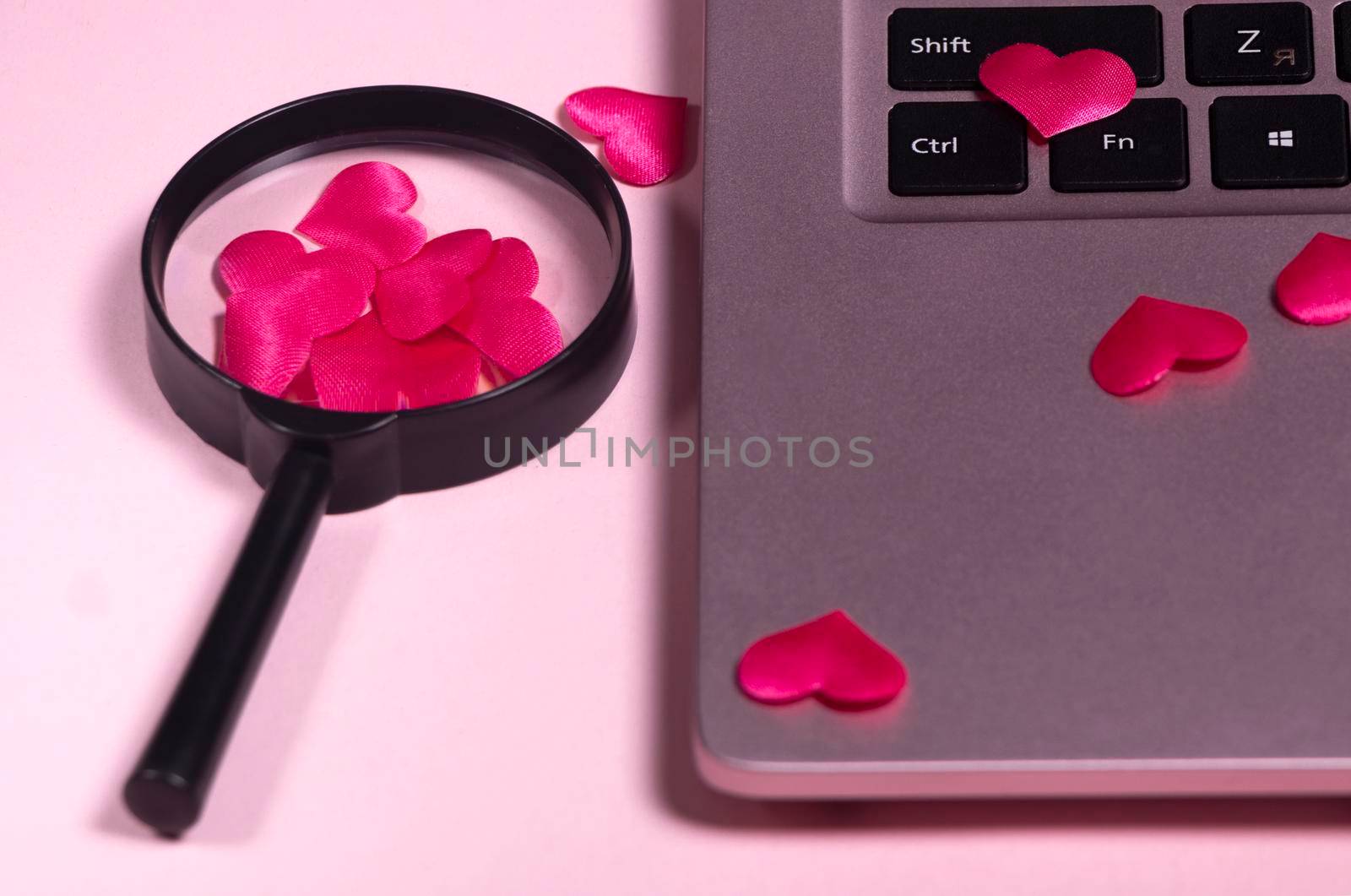 Red heart on the computer keyboard, magnifying glass with handle. by Suietska
