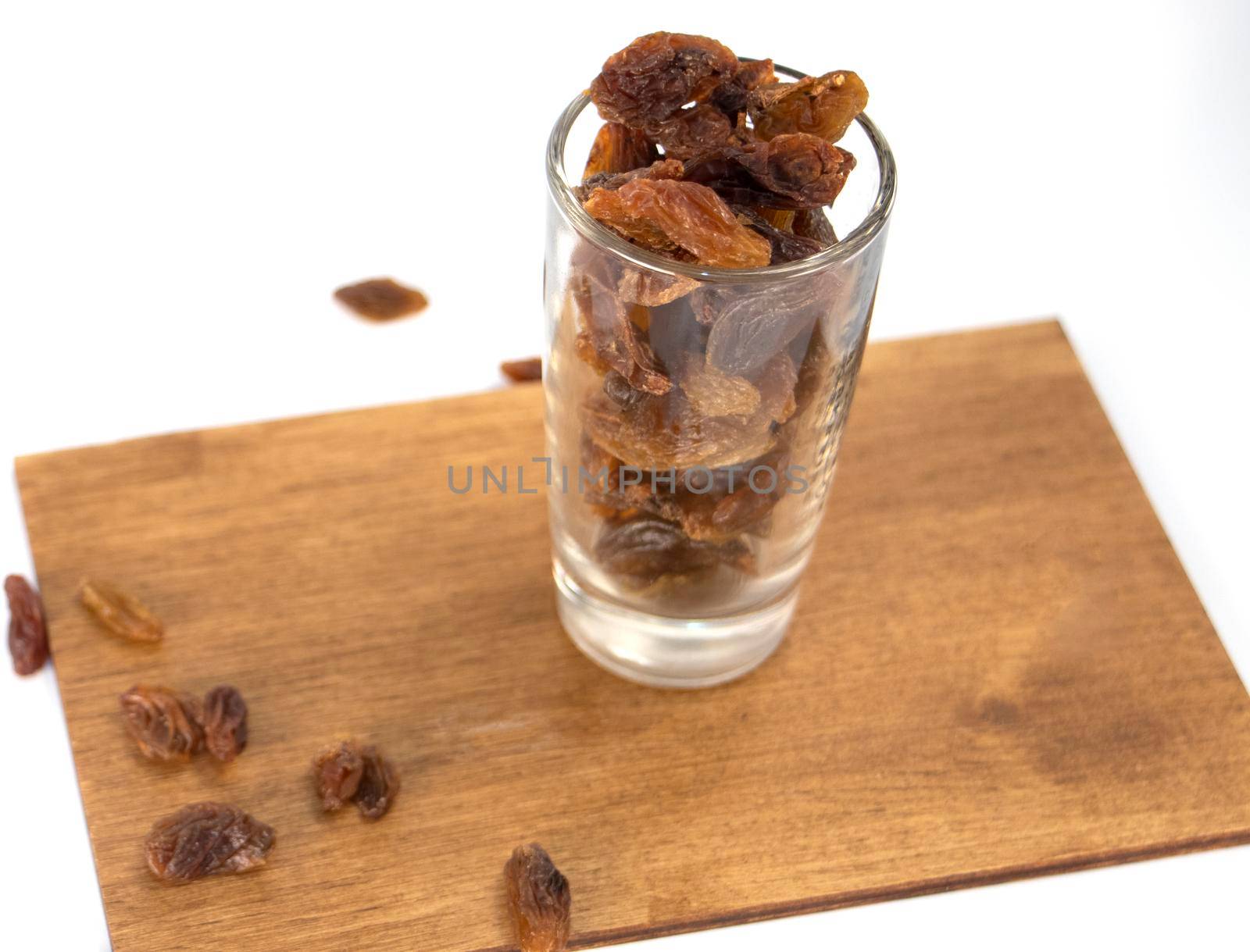 raisins in a glass on a wooden board, scattered. vegetarian dessert. oriental sweets. High quality photo