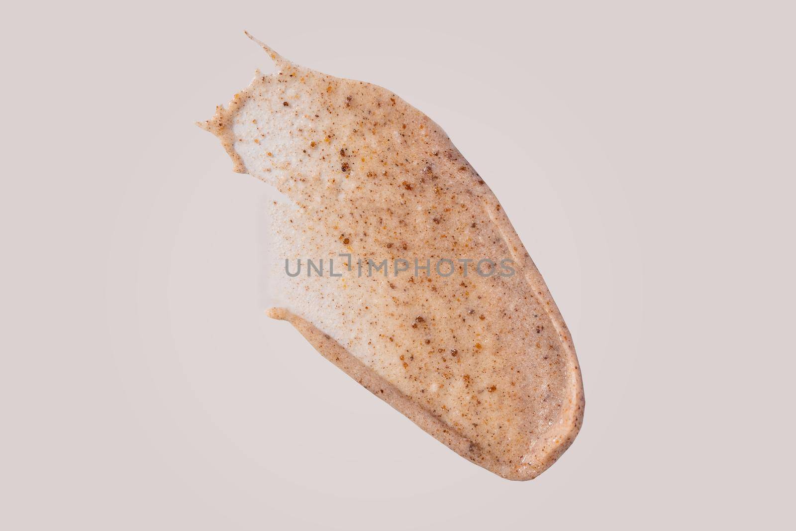 Scrub smear swatch isolated on beige background. Peeling cream smudge with exfoliating particles. Cosmetic skincare product with abrasive particle sample, gentle nude scrub texture isolate.