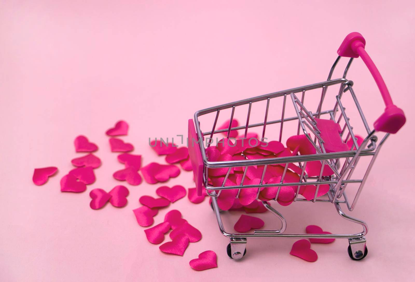 The red Hearts shapes in shopping cart on sweet pink background , the love concept for shopping on valentines day with sweet and romantic moment. High quality photo