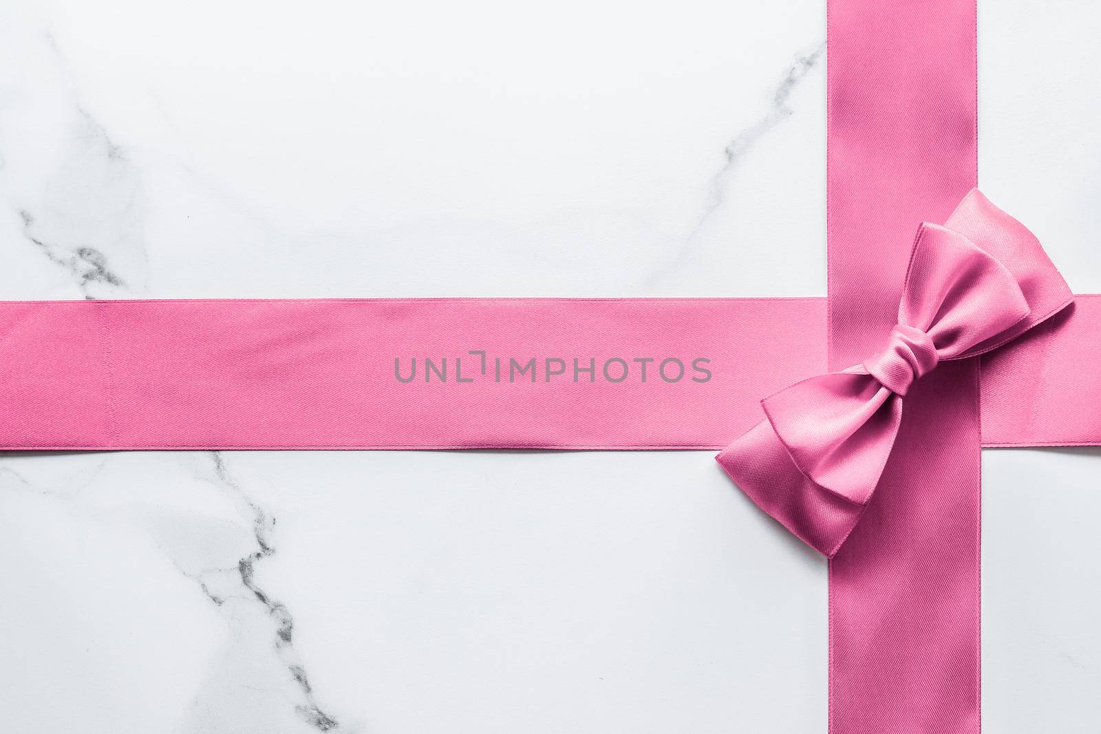 Pink silk ribbon and bow on marble background, girl baby shower present and glamour fashion gift decor for luxury beauty brand, holiday flatlay design by Anneleven