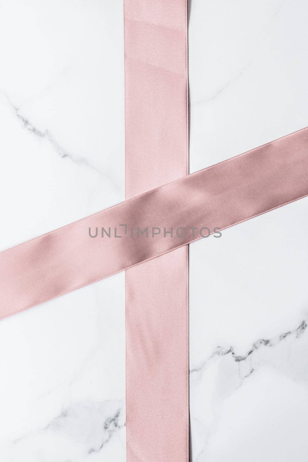 Birthday, wedding and girly branding concept - Beige silk ribbon and bow on marble background, glamour present mockup and fashion gift decoration for luxury beauty brand holiday flatlay design
