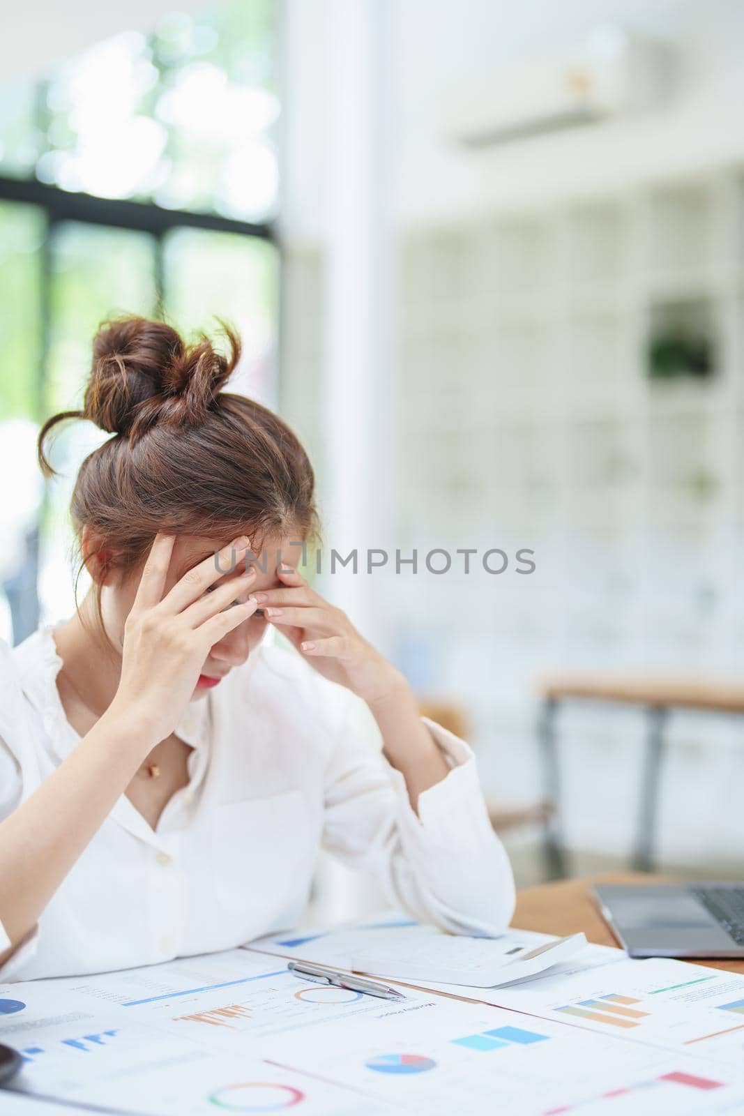 portrait of a women employee shows an anxious and stressed face from working on paperwork by Manastrong