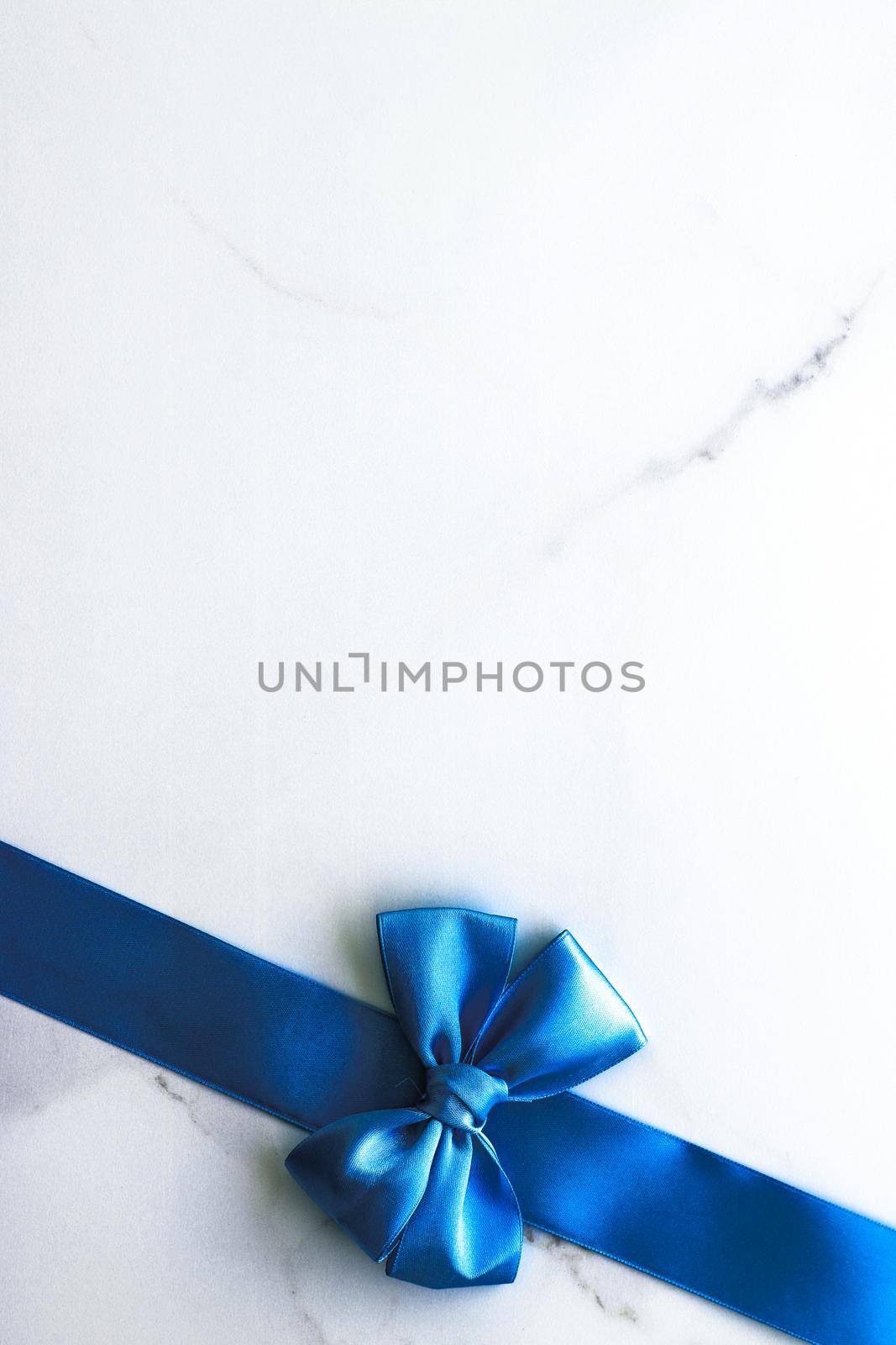Blue silk ribbon and bow on luxury marble background, holiday flatlay backdrop by Anneleven
