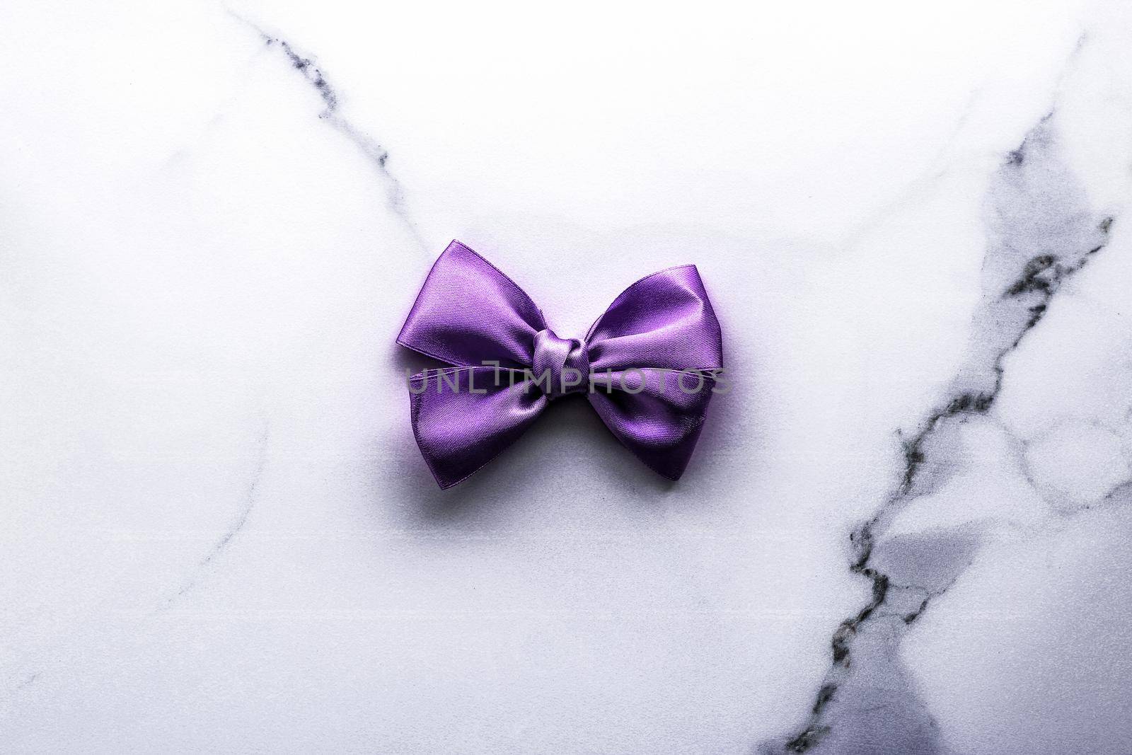 Happy holidays, festive decoration and brand sale promotion concept - Purple silk ribbon and bow on luxury marble background, holiday flatlay backdrop