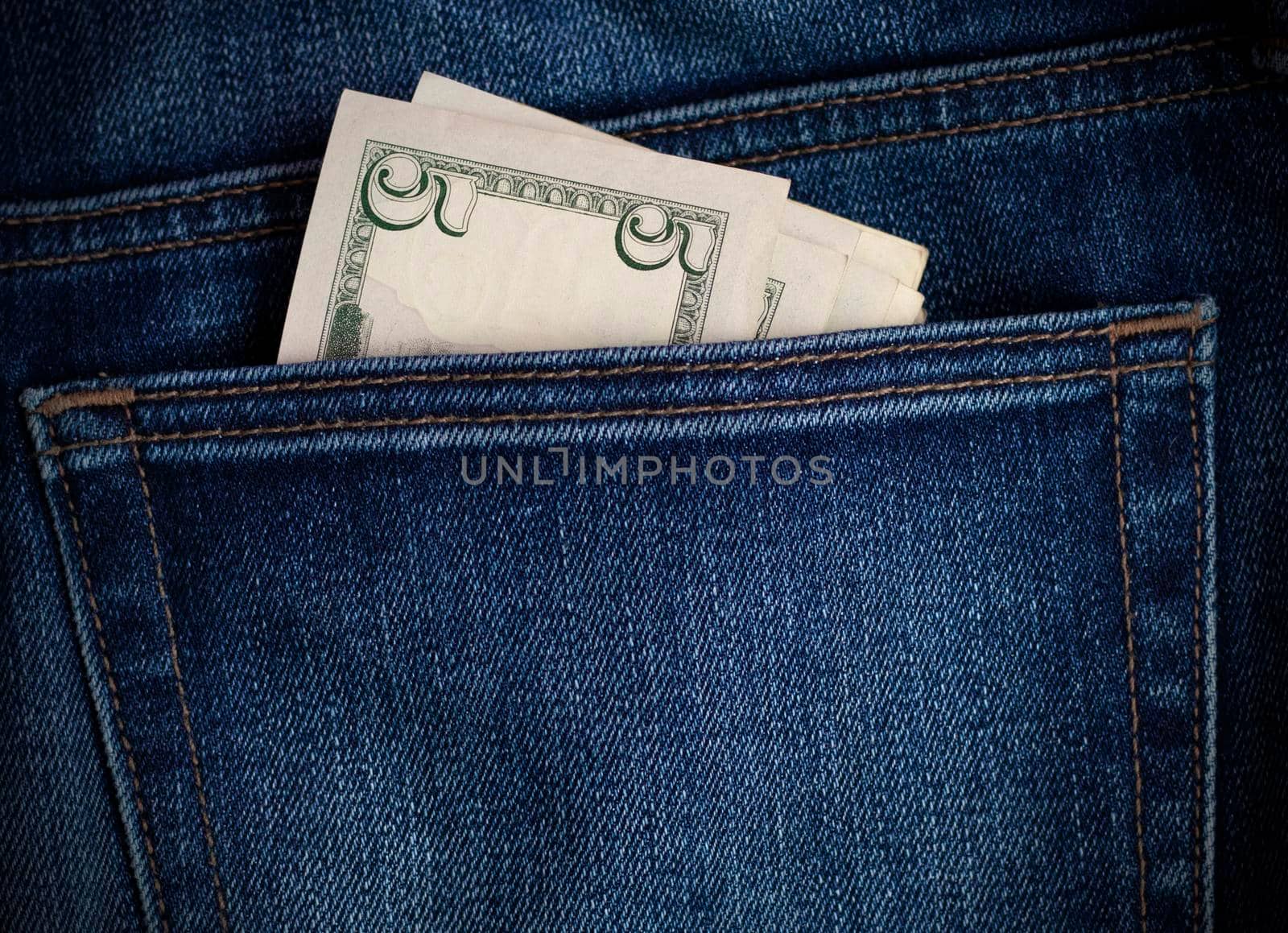 dollar bills visible from the back pocket of his jeans. Money on denim background. Blue sew-on pocket with money. High quality photo