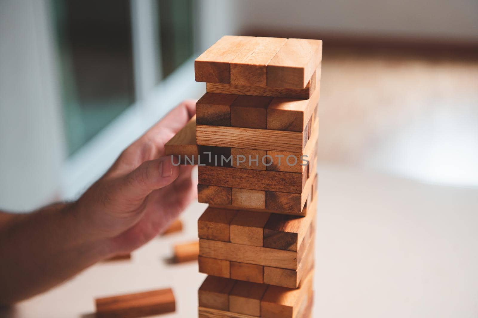 Wooden blocks toy puzzle with human hand on table at home background. Entertainment and business concept.