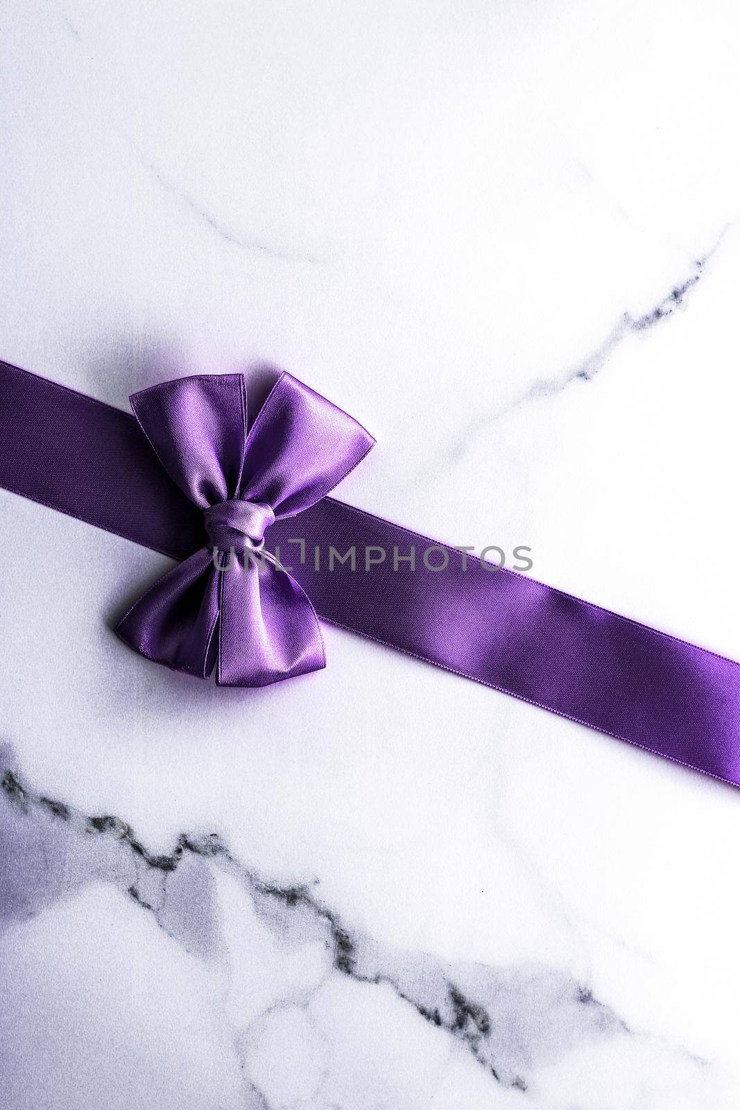 Purple silk ribbon and bow on luxury marble background, holiday flatlay backdrop by Anneleven