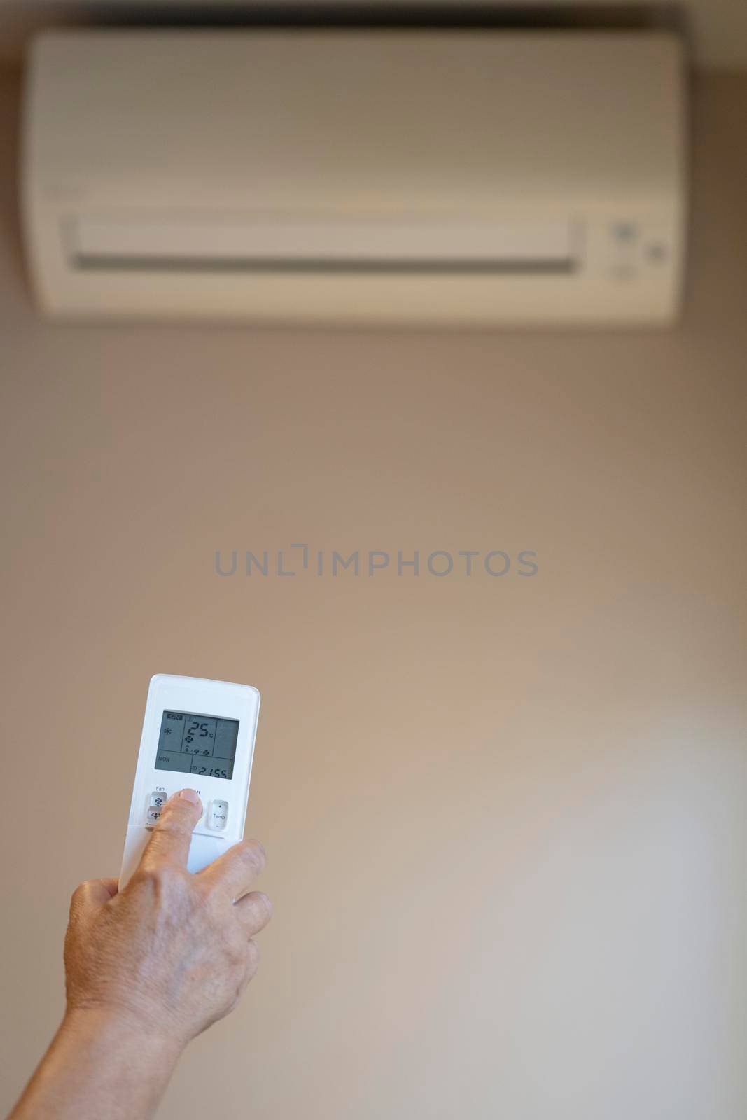 Close-up of old Woman hand operating Air Conditioner With Remote Control. copy space.