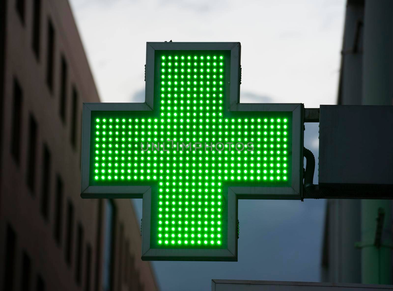 Pharmacy sign in Spain green neon attached to wall.