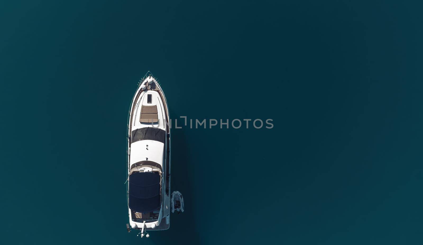Aerial yacht on calm sea. Luxury cruise trip. View from above of white boat on deep blue water. Aerial view of rich yacht sailing sea. Summer journey on luxury ship. by panophotograph