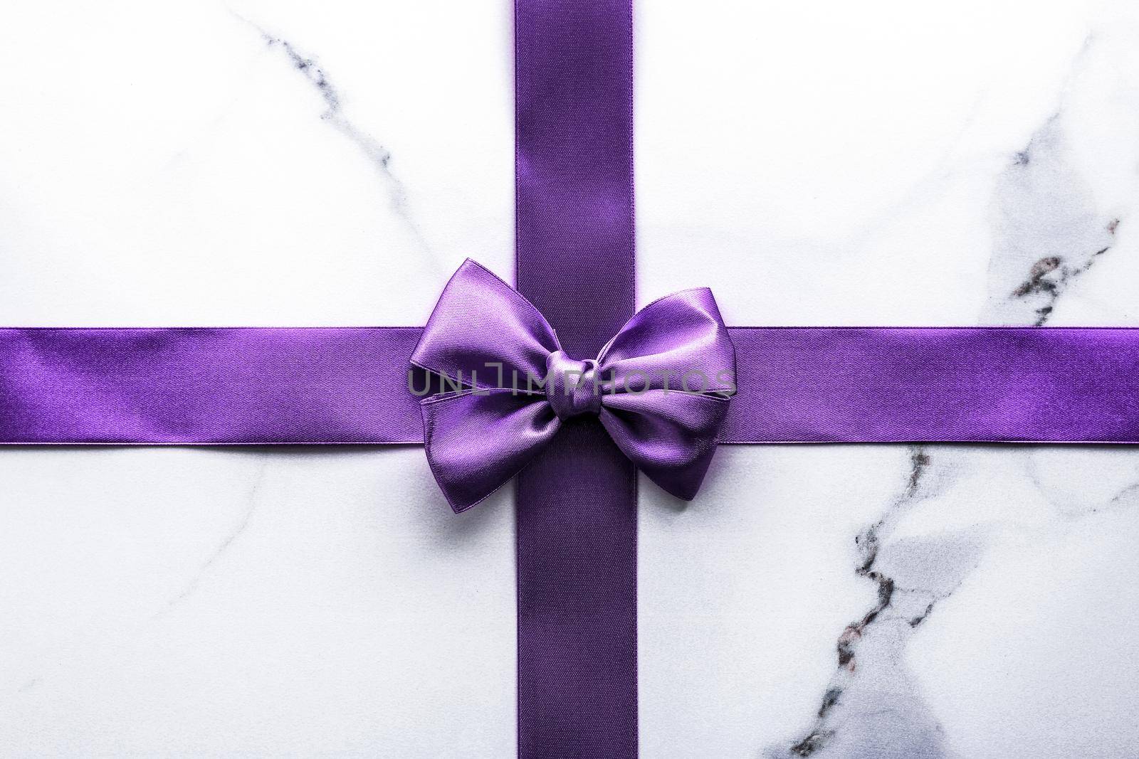 Happy holidays, festive decoration and brand sale promotion concept - Purple silk ribbon and bow on luxury marble background, holiday flatlay backdrop