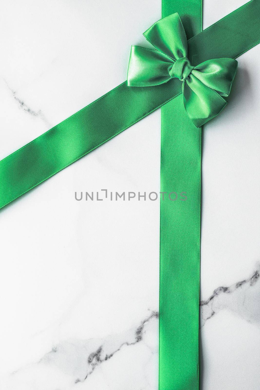 Decorative, birthday and art branding concept - Green silk ribbon and bow on marble background, St Patricks day present or Christmas glamour gift decor for luxury digital brand, holiday flatlay design