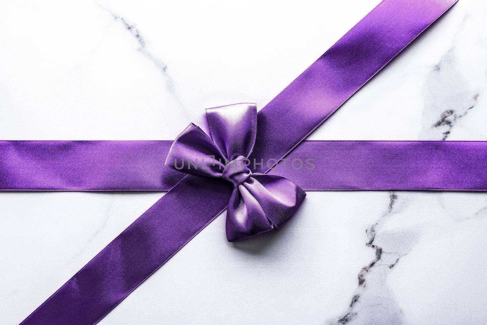 Purple silk ribbon and bow on luxury marble background, holiday flatlay backdrop by Anneleven