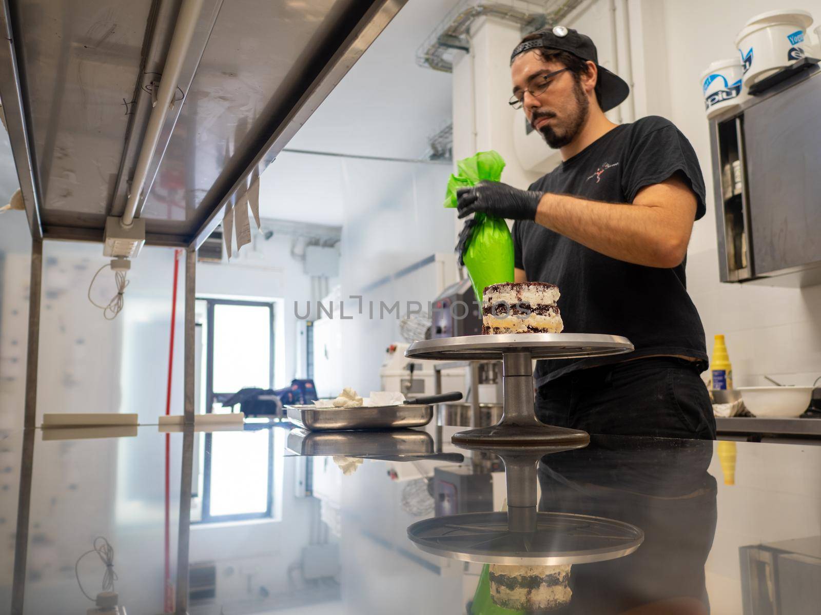 decorator applying buttercream to frosted cake with bag full of cream