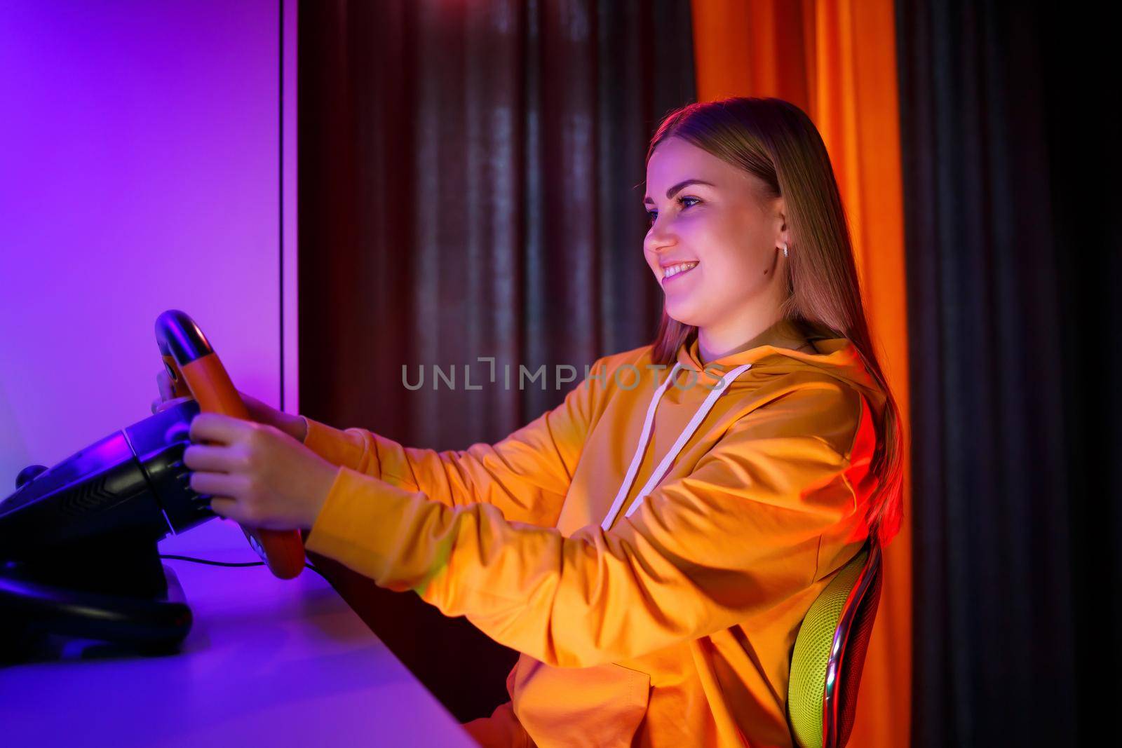 girl gamer playing racing on a computer. She uses a steering wheel. emotional play