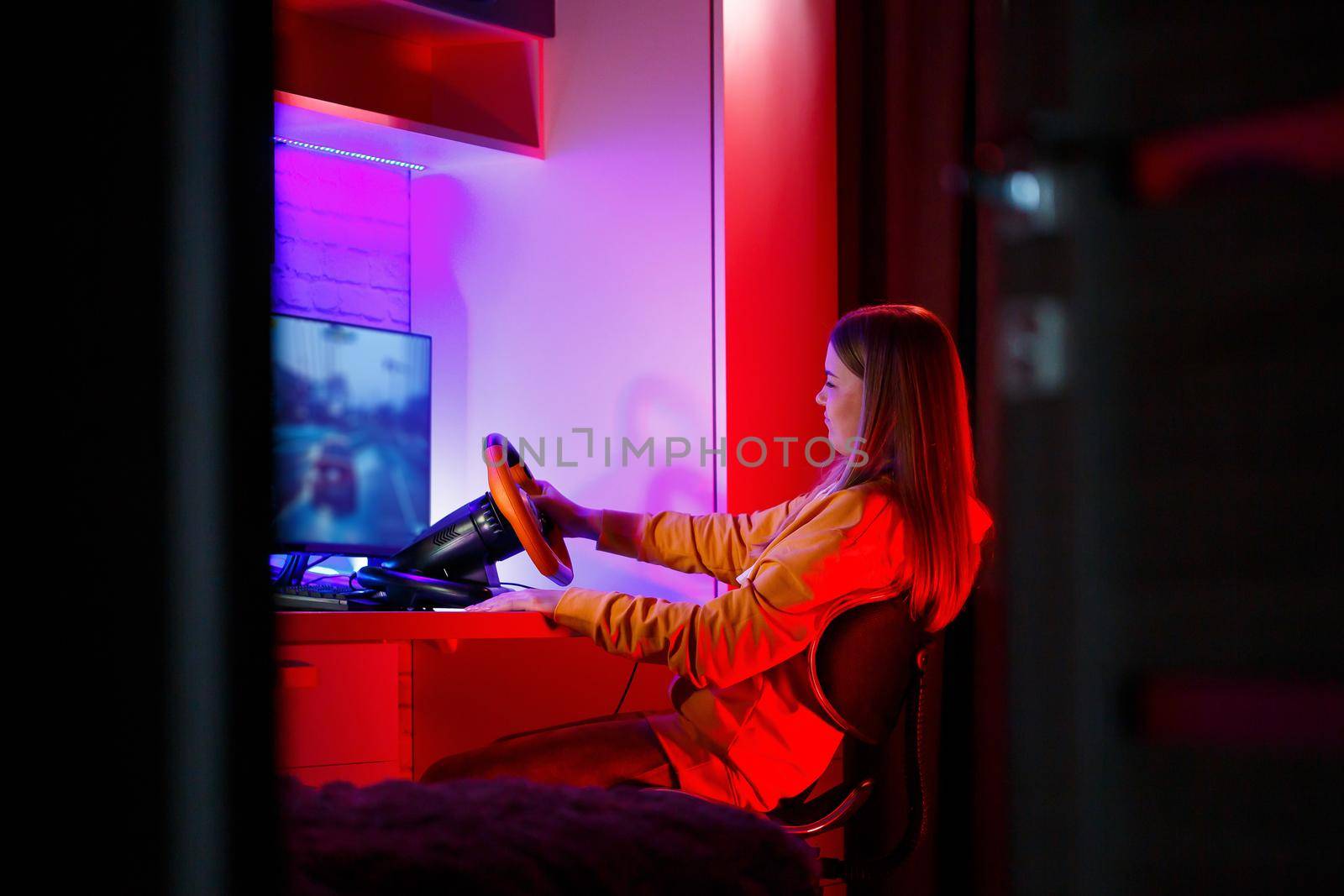 girl gamer playing racing on a computer. She uses a steering wheel. emotional play