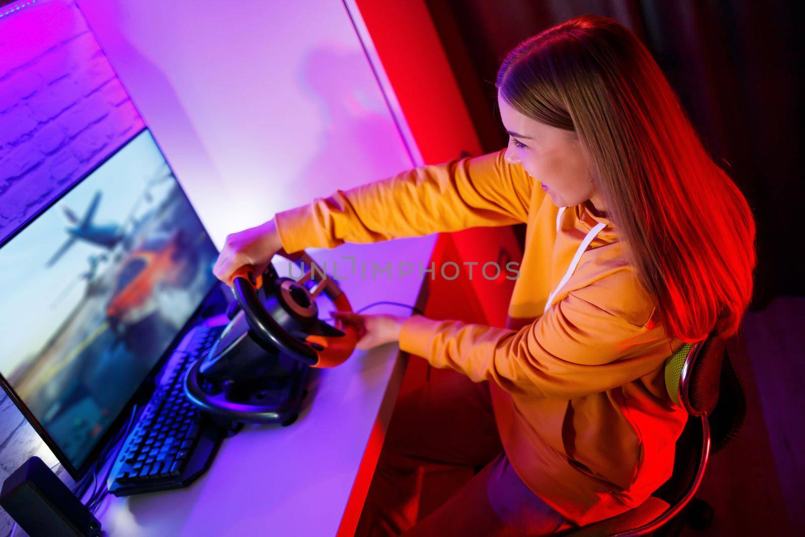 girl gamer playing racing on a computer. She uses a steering wheel. emotional play