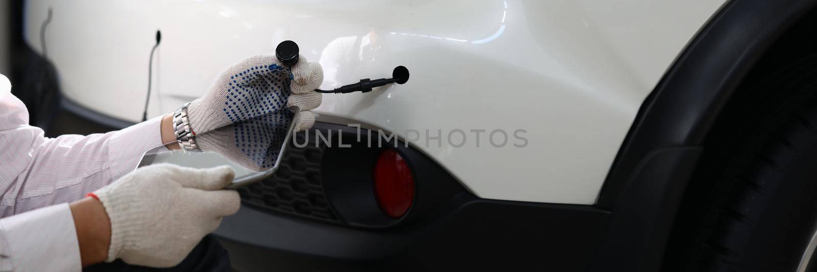 Mechanic installs parking sensors on car closeup by kuprevich