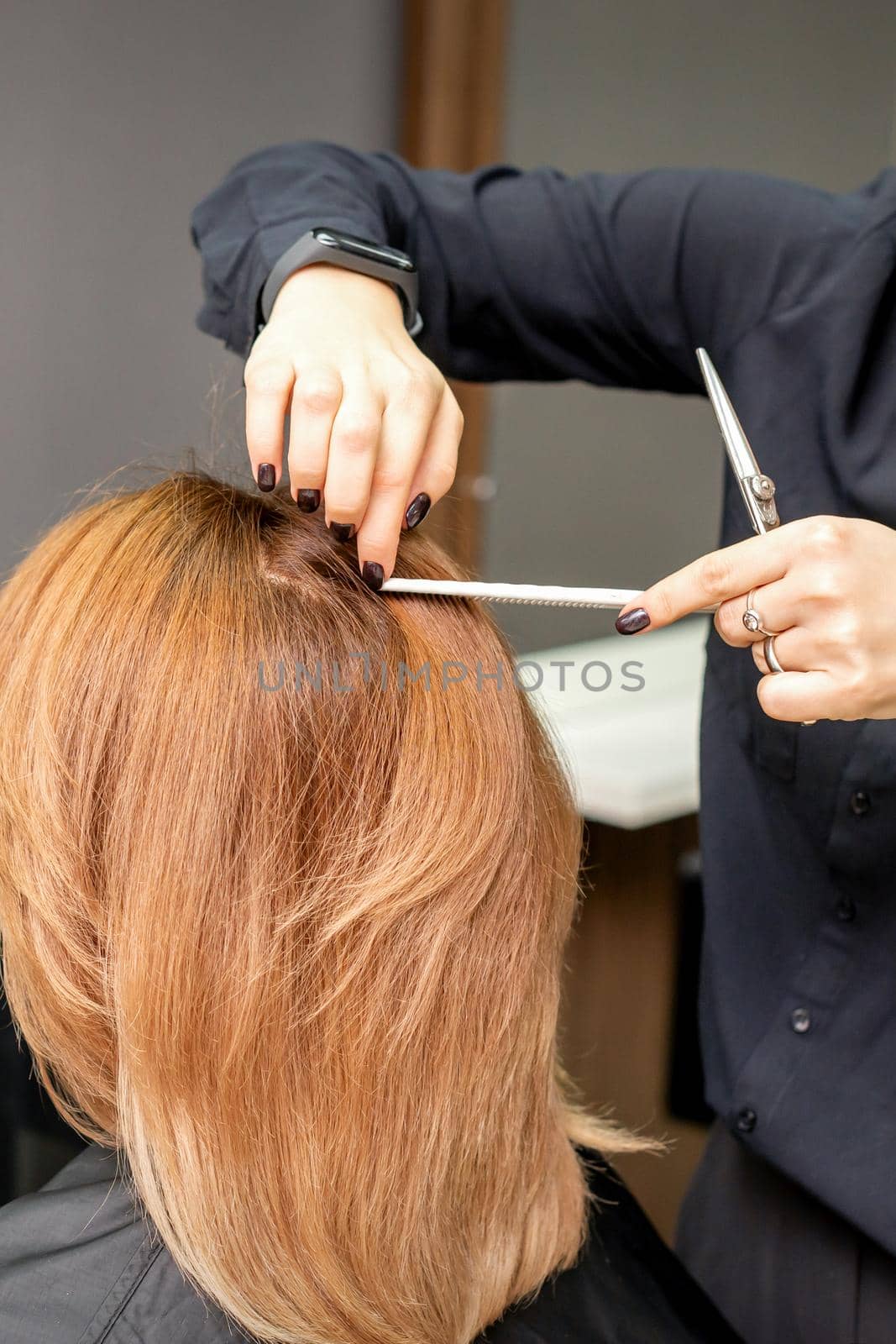 Hairdresser prepares long hair of a young woman to procedures in a beauty salon. by okskukuruza