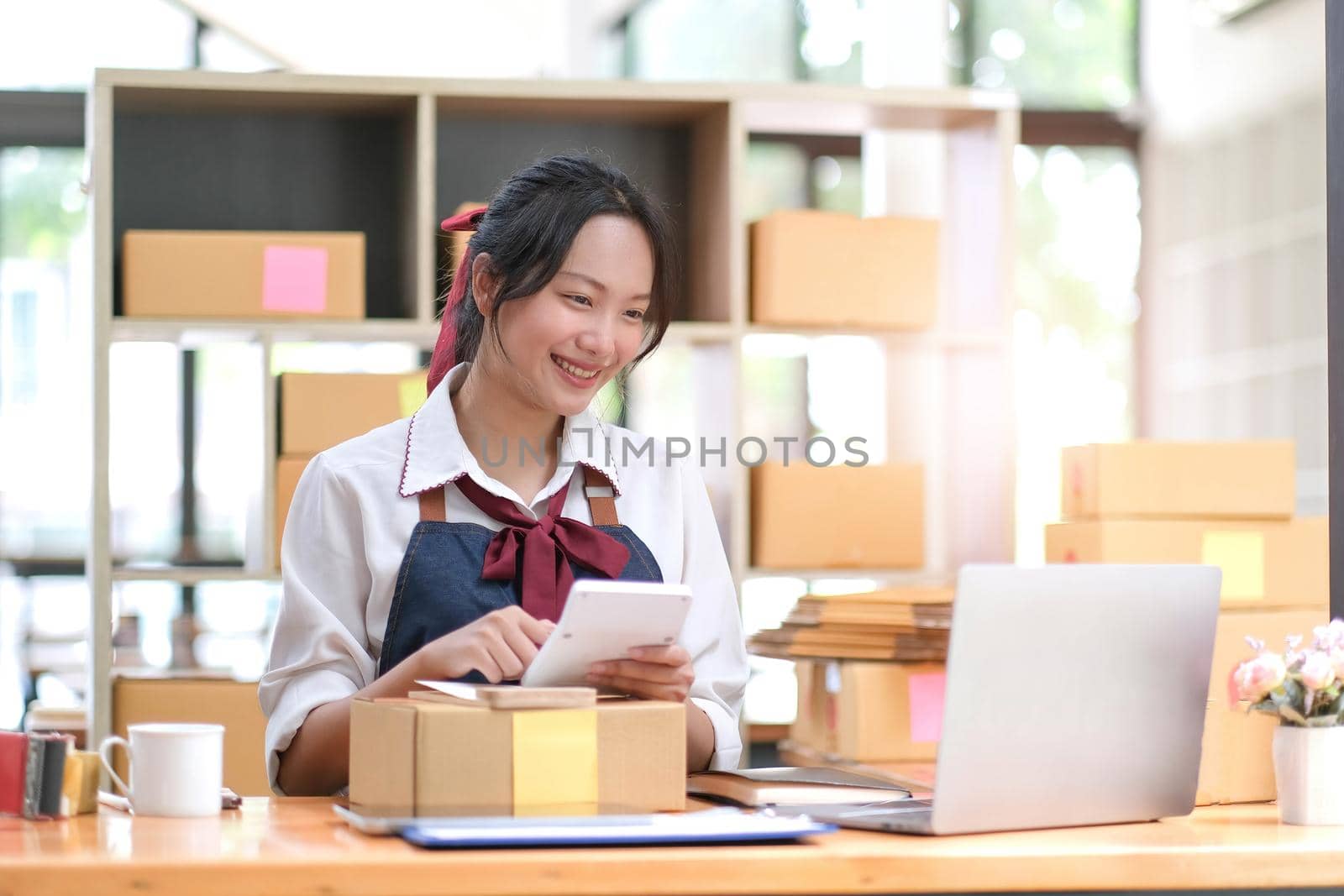 Starting Small business entrepreneur SME freelance,Portrait young woman working at home office, BOX,smartphone,laptop, online, marketing, packaging, delivery, SME, e-commerce concept.