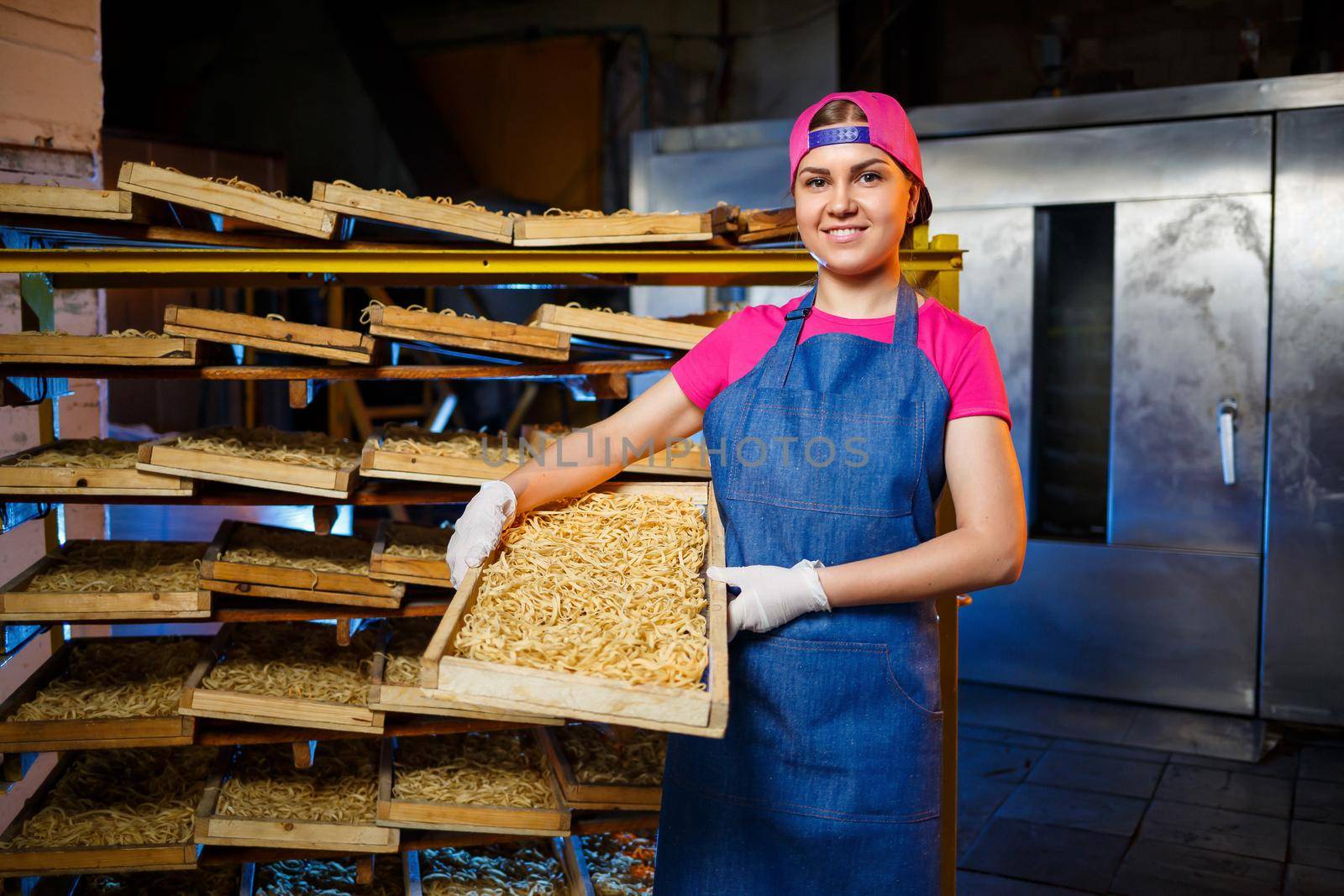Make the noodles. Pasta factory. Spaghetti production. Raw pasta. Worker with a box of pasta. Girl works in the production of pasta
