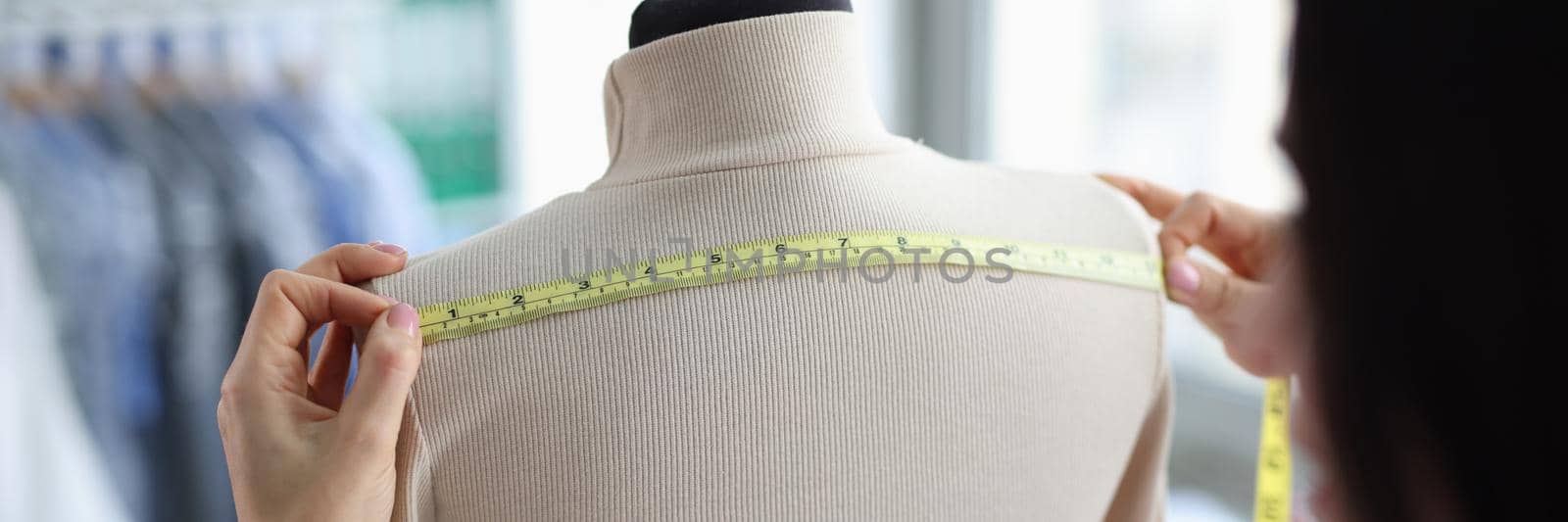 Female tailor takes measurements on mannequin closeup by kuprevich