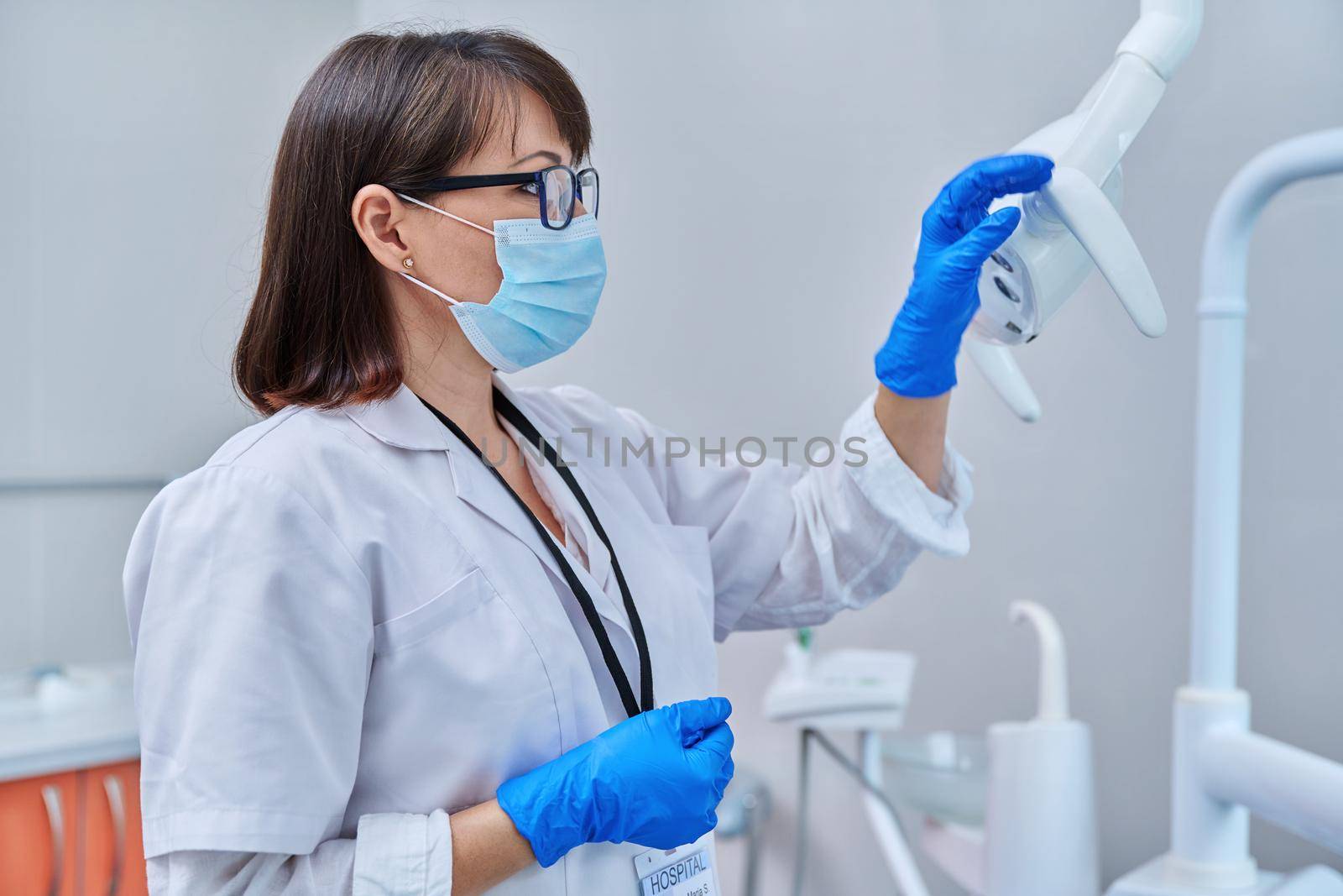 Serious confident female doctor dentist in face mask in dental office by VH-studio