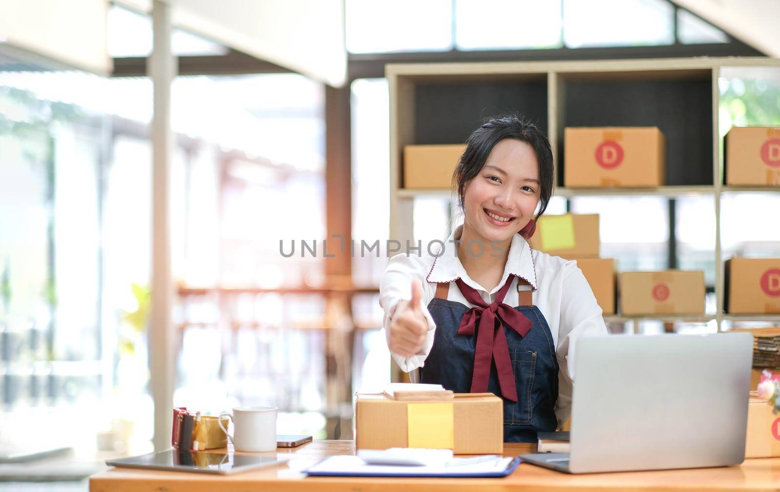 Portrait young attractive asia female owner startup business look at camera work happy with box at home prepare parcel delivery in sme supply chain, procurement, omnichannel commerce online concept..