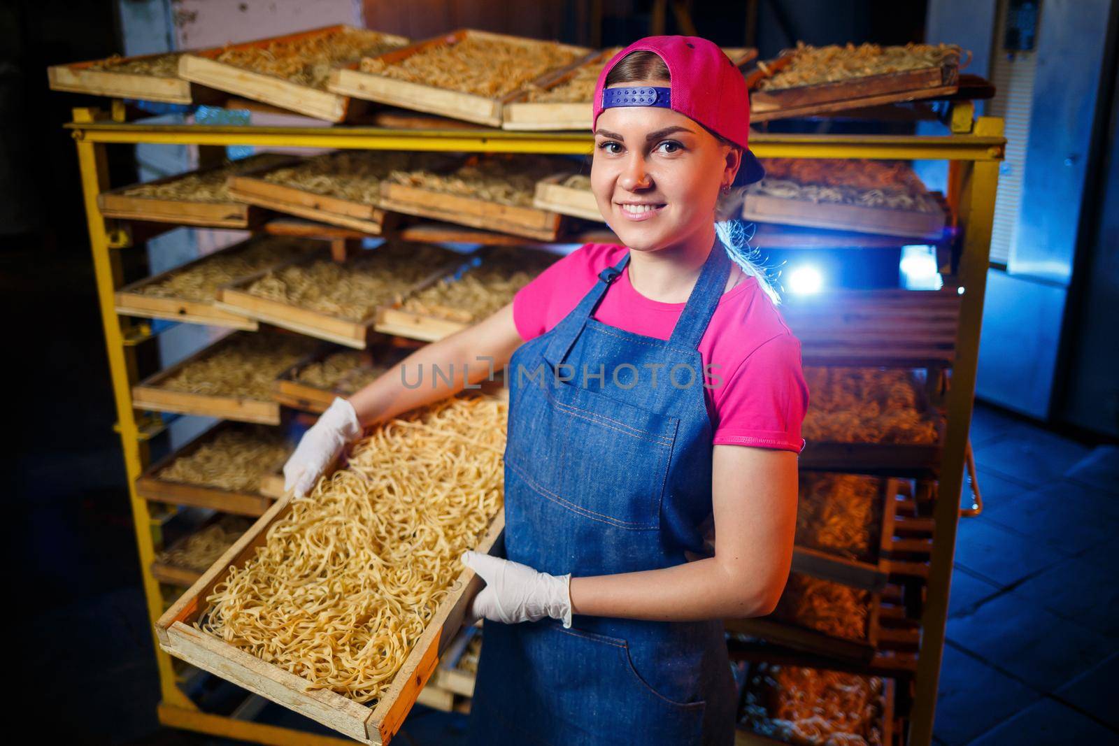 Make the noodles. Pasta factory. Spaghetti production. Raw pasta. Worker with a box of pasta. Girl works in the production of pasta by Dmitrytph