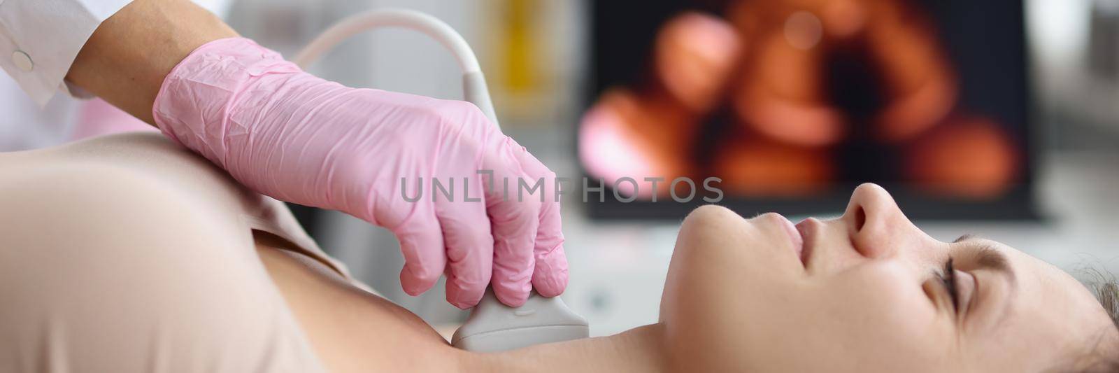 Doctor making ultrasound of thyroid gland to woman patient in clinic by kuprevich