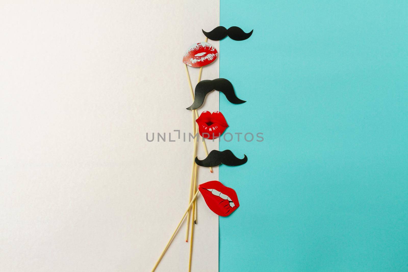 Top view sticks with moustaches and lips. Contrast on mens and womens. White and turquoise background.